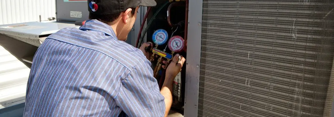 HVAC technician servicing a condenser unit in Carnegie